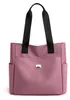 Rosa Stofftasche mit schwarzen Henkeln und zwei Seitentaschen, von vorne gezeigt