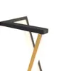 A close-up view of a modern lamp's structure, showing intersecting black and gold metal elements against a white background. Náhľad obrázku produktu