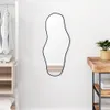 A mirror hanging on a white wall next to a closet and a wooden table. Anteprima dell’immagine prodotto