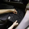 Hands adjusting a black car seat protector inside a vehicle. Produktbild-Vorschau