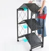 A person is folding a black, three-tiered shelf unit. Anteprima dell’immagine prodotto