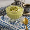 Cremiges Pistazien Dessert in Glasschale garniert mit Kokosraspeln und gehackten Pistazien Produktbild-Vorschau