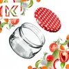 A glass jar and its lid are shown with various vegetables and herbs arranged around them. Produktbild-Vorschau