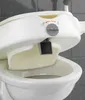 A close-up view of a white toilet seat with armrests, showing a locking mechanism. Produktbild-Vorschau