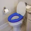 A toilet with a blue raised seat in a bathroom. Anteprima dell’immagine prodotto