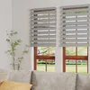 A living room scene with two windows covered by gray zebra blinds, a sofa in the foreground, and a plant on the left. Voir les images du produit