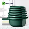 A stack of dark green plastic bowls is shown against a blurred background of a bathroom or kitchen setting. Podgląd zdjęcia produktu