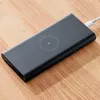 A dark gray power bank with a wireless charging symbol is placed on a wooden surface. A white USB cable is plugged into the power bank. Anteprima dell’immagine prodotto