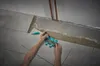 A person is tiling a floor, using a contour gauge to mark a tile. Produktbild-Vorschau