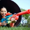 A young person is playing with a toy gun in a large pipe outdoors. Produktbild-Vorschau