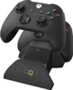 A black Xbox controller charging dock with two controllers on it, set against a white background. Produktbild-Vorschau