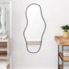 A mirror is hanging on a white wall next to a closet and a wooden table. Anteprima dell’immagine prodotto