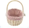 A wicker basket with a red and white checkered fabric lining and a handle, isolated on a white background. Produktbild-Vorschau