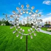 A kinetic wind spinner is displayed in a grassy park with trees and buildings in the background. Anteprima dell’immagine prodotto