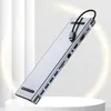 A silver USB-C docking station with multiple ports is displayed diagonally on a white pedestal against a blurred background with soft lighting. Produktbild-Vorschau