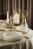 A beautifully set table with dinnerware, candles, and champagne. Produktbild-Vorschau