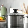 A stainless steel pot with a glass lid on a stovetop. Anteprima dell’immagine prodotto