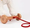 Close-up of a wooden pull toy with a red string, attached to a fluffy white toy animal. Anteprima dell’immagine prodotto