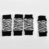 Four dog leg warmers with a zebra pattern are laid out on a white background. Produktbild-Vorschau