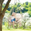 A young girl sits in a hanging chair in a garden. Voir les images du produit