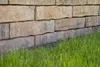 A close-up view of a stone wall with grass in the foreground. Produktbild-Vorschau
