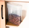 A clear plastic food storage container filled with cereal sits on a shelf. Náhľad obrázku produktu