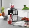 A kitchen counter with a juicer, fruits, and a recipe book. Podgląd zdjęcia produktu