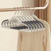 A set of white clothes hangers with gray grips hanging from a rod, with a beige sweater draped over some of them. Voir les images du produit