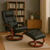 A black leather massage recliner and ottoman are placed on a rug in a room with a bookshelf and a wooden cabinet. Produktbild-Vorschau