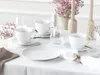 A table setting with white porcelain cups, saucers, and plates, decorated with pink flowers and wooden candle holders. Náhľad obrázku produktu