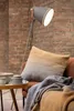 A cozy living room scene with a sofa, throw blanket, pillow, and a floor lamp. Produktbild-Vorschau