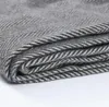 A close-up, folded view of a grey herringbone patterned blanket. Anteprima dell’immagine prodotto