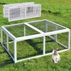 A rabbit run is set up on a grassy lawn, with a rabbit sitting in front of it. Two other rabbit runs are visible in the background. Produktbild-Vorschau