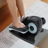 A person's legs and feet are using a black and blue pedal exerciser on a striped rug. Podgląd zdjęcia produktu