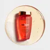 A bottle of Kerastase shampoo is shown on a clear liquid background with some foam. Produktbild-Vorschau