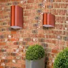 Two modern outdoor wall lights mounted on a brick wall, with a potted plant in the foreground. Produktbild-Vorschau