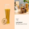 A collage showing a tall glass jar filled with spaghetti on the left, and several smaller glass jars with various food items and a kitchen scale on the right. A section at the bottom right contains marketing text and an icon. Produktbild-Vorschau
