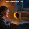 A young boy looks at a moon-shaped lamp with a digital clock displaying 09:00. Produktbild-Vorschau