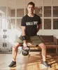 A man is performing a kettlebell exercise in a home gym setting. Produktbild-Vorschau