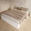 A white bed with a beige duvet and pillows in a bedroom. Produktbild-Vorschau