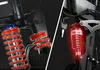 A split image showing close-ups of bicycle suspension components, one side in shadow and the other illuminated with a red glow. Produktbild-Vorschau