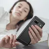 A person in bed holding a phone with a protective case. Produktbild-Vorschau