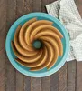 A bundt cake on a blue plate, placed on a wooden surface, with a patterned napkin to the side. Podgląd zdjęcia produktu