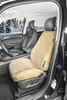 Interior of a car with a sheepskin seat cover on the driver's seat, with a snowy forest visible through the windows. Produktbild-Vorschau
