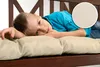 A young boy is lying on a cushioned bench. Produktbild-Vorschau