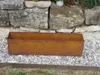 A rusty metal planter box sits on a bed of gravel in front of a stone wall. Anteprima dell’immagine prodotto