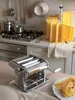 A kitchen scene with a pasta maker, drying pasta, and cooking utensils. Anteprima dell’immagine prodotto