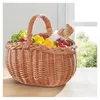 A wicker basket filled with fresh produce and a baguette, placed on a wooden surface near a window. Produktbild-Vorschau