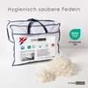 A duvet in its packaging, with loose feathers scattered in the foreground. Produktbild-Vorschau