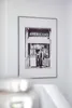 A framed black and white photograph of a man standing in front of an "AMERICANO ICE CREAM" stand is displayed on a white wall. Anteprima dell’immagine prodotto